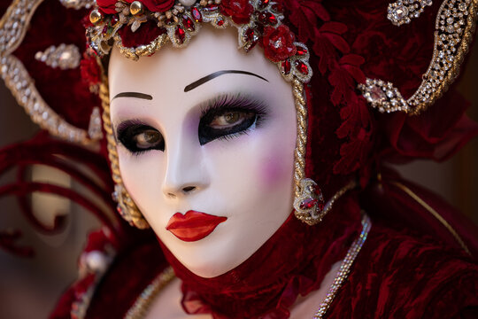 Riquewihr, France - 04 July 2026: View of a person wearing an elaborate red velvet costume and a detailed Venetian-style mask with intricate floral decorations and sparkling jewels.