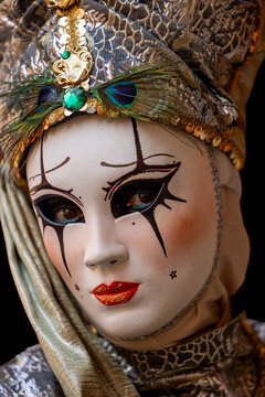 Riquewihr, France - 04 July 2026: View of a person wearing an elaborate carnival mask with peacock feathers, gold sequins, and dramatic makeup.