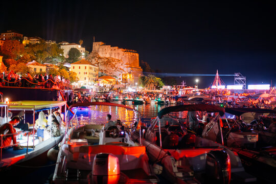 View of the illuminated Kanli Kula fortress overlooking a bustling harbor filled with boats and people during a summer festival in Herceg Novi, Opstina Herceg Novi, Montenegro.