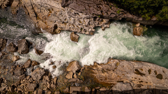 Aerial view of a fast-flowing river with white water rapids rushing over rugged rocks in the wilderness of Patagonia Puerto Williams, Magallanes, Chile.