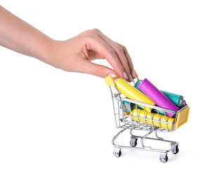Woman putting alkaline batteries into mini shopping cart on white background, closeup. Waste recycling © New Africa