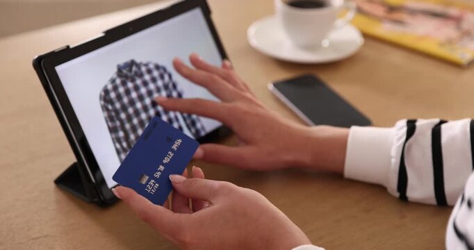 Online store. Woman with credit card using tablet at wooden table indoors, closeup