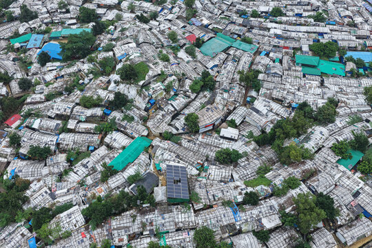 Aerial view of Rohingya Camp with dense rows of makeshift shelters, tarpaulin roofs, and green solar panels in Ukhia, Chittagong Division, Bangladesh.