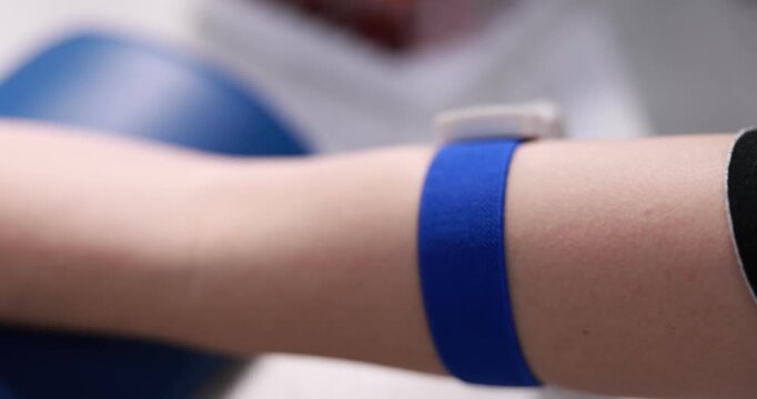 Blood analysis. Laboratory worker putting test tube into rack and woman with medical bandage on her hand, selective focus. Camera moving forward