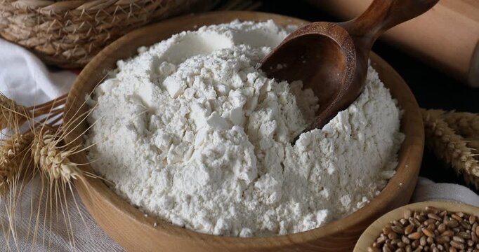 Wheat flour, grains, spikes and rolling pin on black table, closeup. Camera moving in