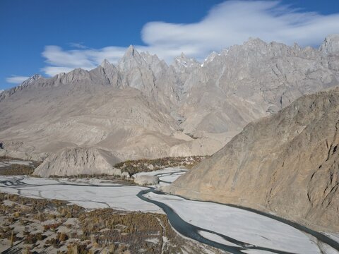 Aerial view of Haldi Cones with rugged mountain peaks, a winding riverbed, and rocky terrain in Pakistan.