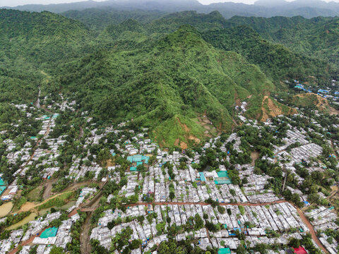 Cox's Bazar, Chittagong Division, Bangladesh - 17 July 2026: Aerial view of the dense settlement in Cox's Bazar nestled against lush green hills, featuring rows of small shelters and narrow pathways.