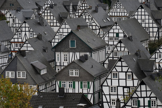 View of traditional half-timbered houses with slate roofs and black and white timber framing in a dense historic village in Germany.