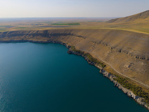 Aerial view of the turquoise waters of Meke Lake surrounded by arid volcanic slopes and dry plains in Karapinar, Konya, Turkey.