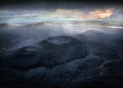 Aerial view of the volcanic craters in Fjallabak Nature Reserve with dark lava fields and dramatic light breaking through the clouds in Rangarthing ytra, Iceland.