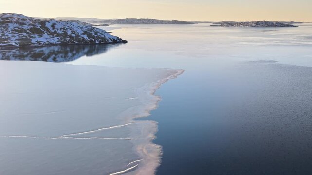 Aerial view of Stora Amundon with icy waters and snow-covered coastline during the golden hour in Hovas, Vastra Gotalands lan, Sweden.