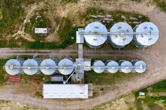 Aerial view of grain bins arranged in a row on a farm in Poland.