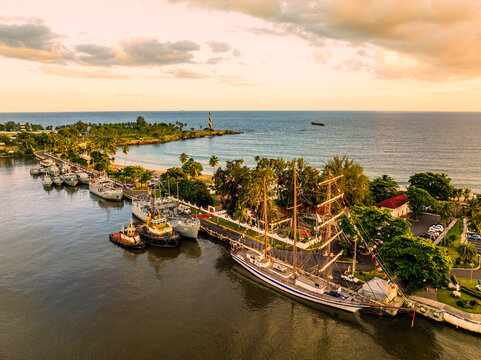 Aerial view of the Club Naval Para Oficiales featuring a large sailing ship and patrol vessels docked along the coastline in Santo Domingo Este, Santo Domingo Provinc, Dominican Republic.