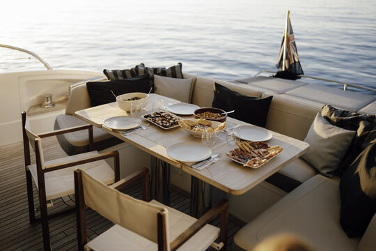 Mallorca, Balearic Islands, Spain - 20 April 2024: View of a dining table set with appetizers and drinks on the deck of a luxury yacht at sunset.