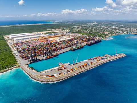 Aerial view of DP World Dominicana port facility with stacked shipping containers, large cargo ships, and cranes along the turquoise coastline in Boca Chica, Santo Domingo, Dominican Republic.