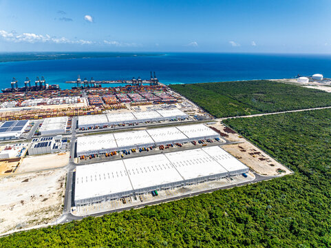 Aerial view of DP World Dominicana port facility featuring large warehouses, shipping containers, and cranes along the coastline in Boca Chica, Santo Domingo, Dominican Republic.