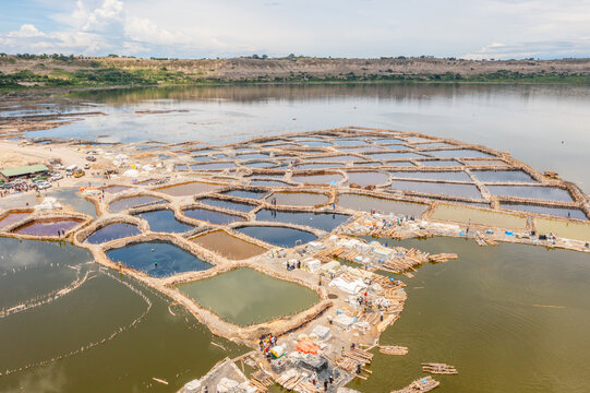 Aerial view of the colorful salt evaporation ponds at Lake Katwe with workers on wooden walkways in Kasese, Western Region, Uganda.