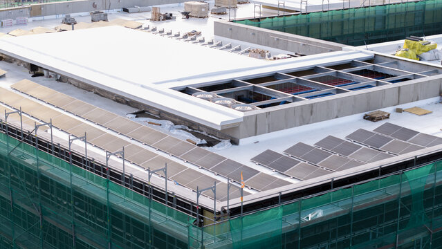 Aerial view of an AI data center under construction featuring solar panels and HVAC units on the roof, surrounded by green safety netting in Krakow, Lesser Poland Voivode, Poland.
