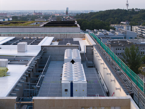 Aerial view of an AI data center rooftop featuring industrial cooling units, solar panels, and green roof sections overlooking the urban landscape of Krakow, Lesser Poland Voivode, Poland.