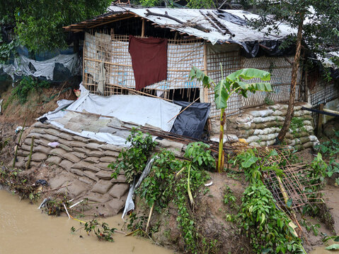 Cox's Bazar, Bangladesh - 19 July 2026: View of a makeshift shelter constructed from bamboo, plastic tarps, and sandbags on a muddy embankment in a refugee camp.