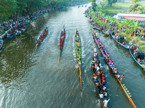 Gopalganj, Bangladesh - 30 October 2023: Aerial view of a traditional boat race on a river, with long narrow boats filled with rowers competing, surrounded by spectators lining the riverbanks.