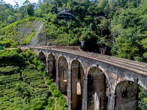 Aerial view of the historic Nine Arch Bridge surrounded by lush tea plantations and dense forest in Demodara, Uva Province, Sri Lanka.
