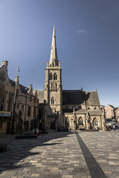 Durham, England, United Kingdom - 13 July 2026: View of St Nicholas Church in the historic market square with stone architecture, arched windows, and a tall spire under a clear blue sky.