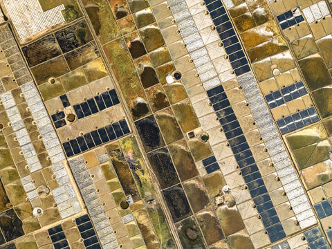 Cox's Bazar, Chittagong Division, Bangladesh - 28 February 2025: Aerial view of Kutubdia Island salt pans with geometric evaporation ponds, varying water levels, and textured earth patterns.