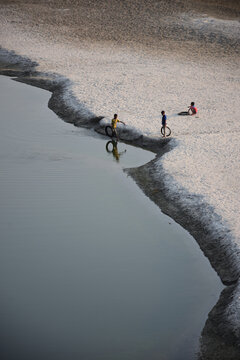 Kushtia District, Khulna Division, Bangladesh - 10 March 2020: View of children playing with tires on the sandy riverbank.