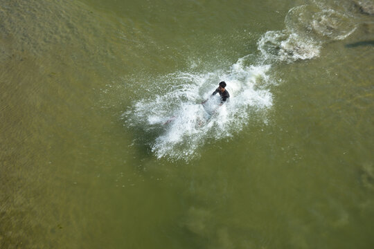 Kushtia District, Khulna Division, Bangladesh - 10 March 2020: View of a man splashing in the river water, creating ripples and spray on a sunny day.
