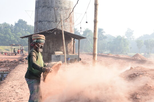 Kushtia District, Bangladesh - 28 November 2020: View of a worker wearing a face mask while sifting soil at a brick kiln in a rural area.