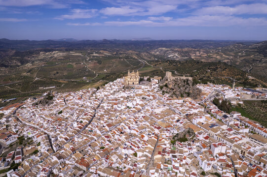 Aerial view of the historic white village of Olvera with its hilltop church and castle, surrounded by rolling hills and olive groves in Olvera, Andalusia, Spain.