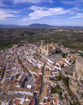 Aerial view of the town of Olvera, featuring the prominent Church of Our Lady of the Incarnation and historic castle ruins, surrounded by white-washed houses in Olvera, Andalusia, Spain.