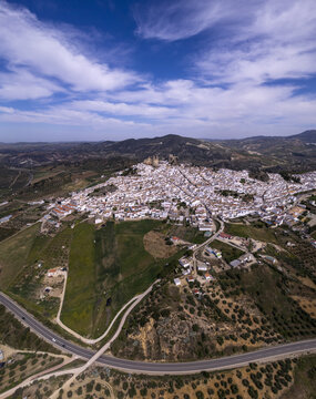 Aerial view of the historic white town of Olvera with its castle perched on a hilltop, surrounded by rolling hills and olive groves in Olvera, Andalusia, Spain.