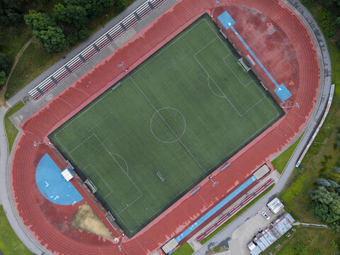 Aerial view of a sports centre with a green soccer field and a red running track wet from rain in Wieliczka, Lesser Poland Voivode, Poland.