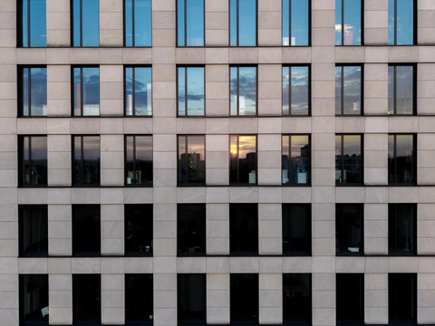 Aerial view of the modern stone facade of a building with grid-like windows reflecting the sunset sky, Krakow, Lesser Poland Voivode, Poland.