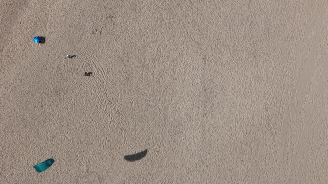 Aerial view of people and kiteboarding equipment on the sandy beach of Praia do Guincho in Cascais, Lisbon, Portugal.