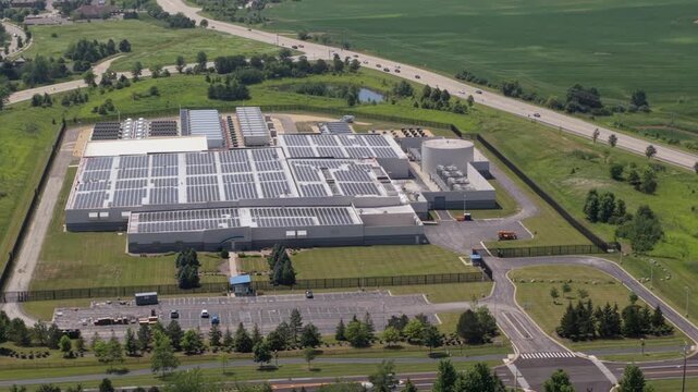 Aerial view of a large data center facility with rooftop solar panels, a parking lot, and surrounding green fields in Volo, Illinois, United States.