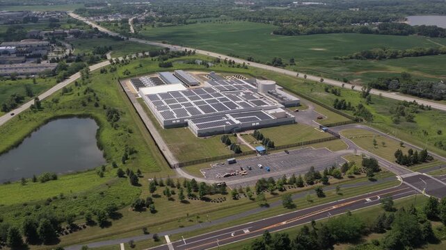 Aerial view of a modern data center facility surrounded by green fields and a small pond in Volo, Illinois, United States.
