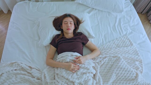 Young woman sleeping on white bed with blanket pillow calm peaceful lying in cozy home bedroom resting relaxed morning natural light soft bedding indoor scene