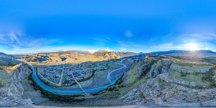 Aerial view of El Chalten town nestled in the Patagonia valley with the Fitz Roy mountain range in the background and a winding river, El Chalten, Santa Cruz, Argentina.
