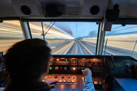 View of a train driver operating the controls in the cab of a high-speed train with motion blur on the tracks at Amsterdam Airport Schiphol, Schiphol, Noord-Holland, Netherlands.