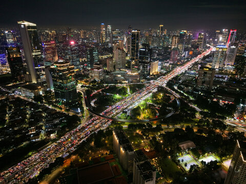 Aerial view of Semanggi Interchange at night with heavy traffic flowing through the iconic cloverleaf junction surrounded by skyscrapers and city lights in Setiabudi, Jakarta, Indonesia.