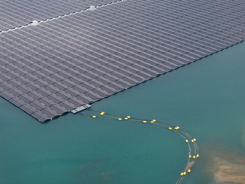 Aerial view of a floating solar farm with rows of photovoltaic panels on calm water in the Netherlands.