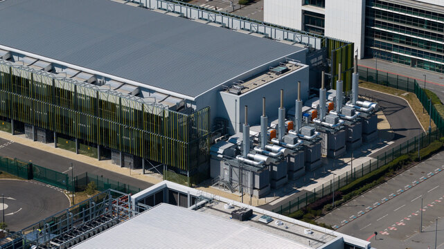 Aerial view of the Kao Data campus featuring modern industrial architecture, rows of cooling units, and fenced perimeter in Harlow, England, United Kingdom.