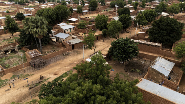 Aerial view of a rural village with traditional mud brick houses, dirt paths, and lush trees in Dambatta, Kano, Nigeria.