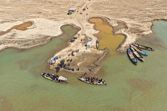 Aerial view of Jadukata River with local people boarding and disembarking from wooden boats along the sandy riverbanks in Sunamganj, Sylhet Division, Bangladesh.