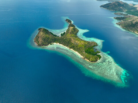 Aerial view of CYC Beach on a tropical island surrounded by vibrant turquoise coral reefs and deep blue ocean waters in Coron, Mimaropa, Philippines.