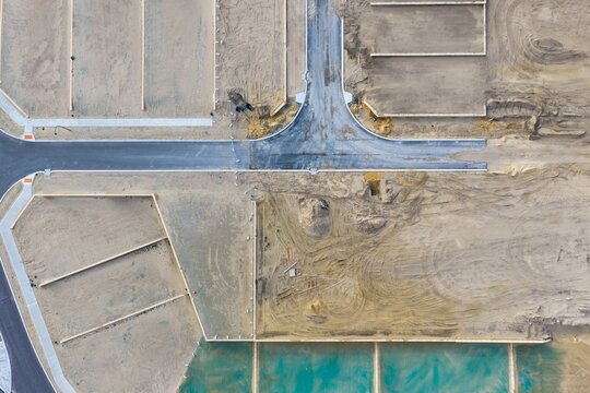 Aerial view of a residential development site under construction with newly paved roads, marked plot boundaries, and sandy soil in Perth, Western Australia, Australia.