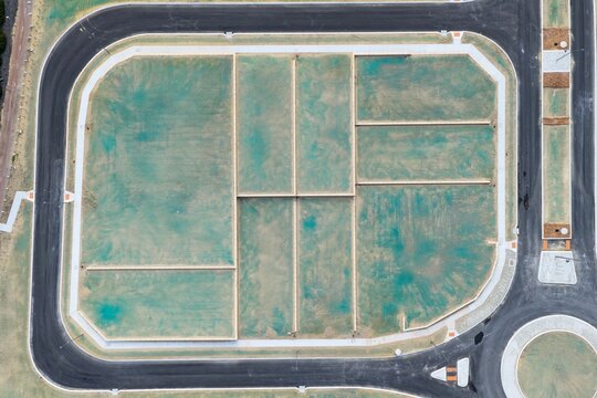 Aerial view of a new residential development site with subdivided plots, green hydroseeding, and paved roads in Perth, Western Australia, Australia.
